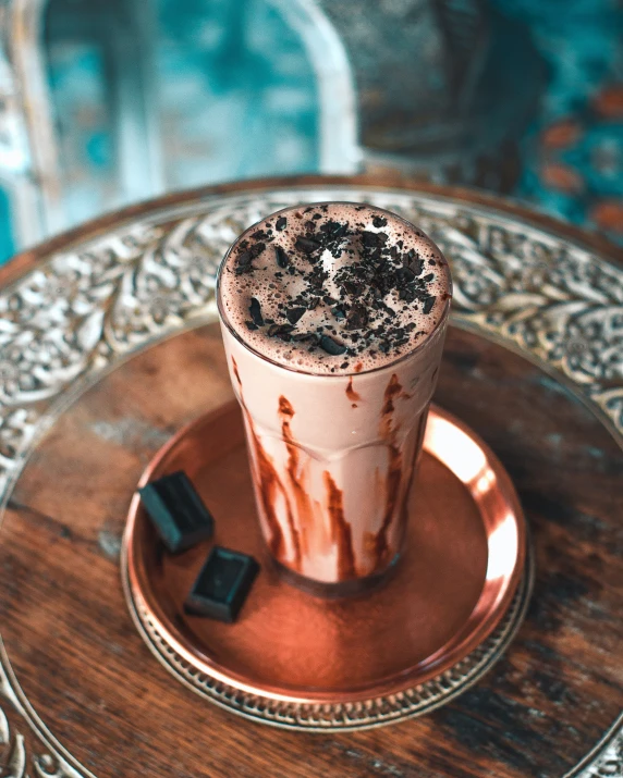 a glass filled with a chocolate drink on a plate