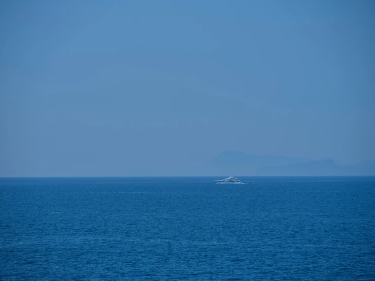 an open ocean with a boat and a small island in the distance