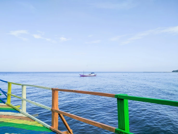 a pier overlooks the ocean with boats in the distance