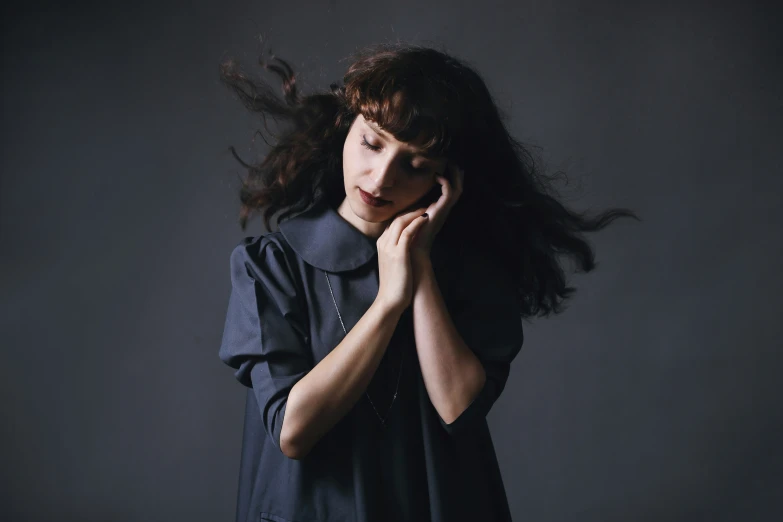 a woman standing with her hair blowing behind her face