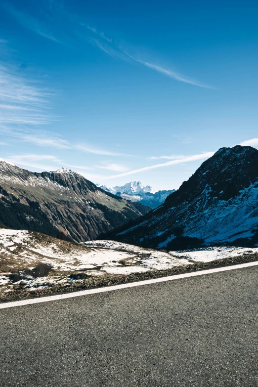 a long and empty highway surrounded by snow capped mountains