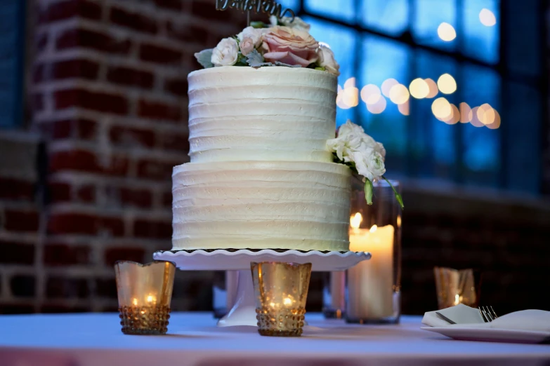 a white wedding cake sitting on top of a table next to two candles