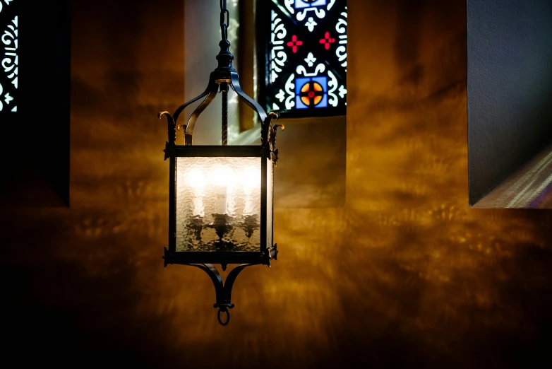 an old lantern hanging next to some stained glass