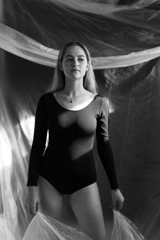 black and white image of woman in bodysuit holding large sheet
