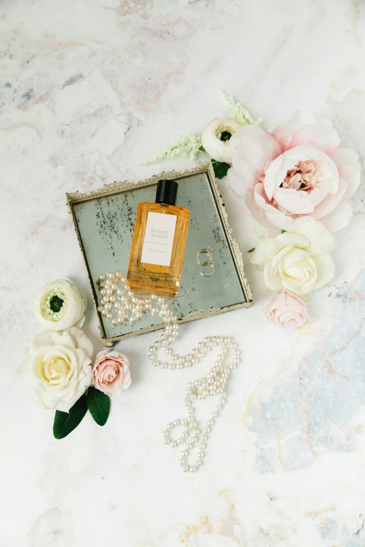 a perfume bottle is next to a floral arrangement on a marble surface