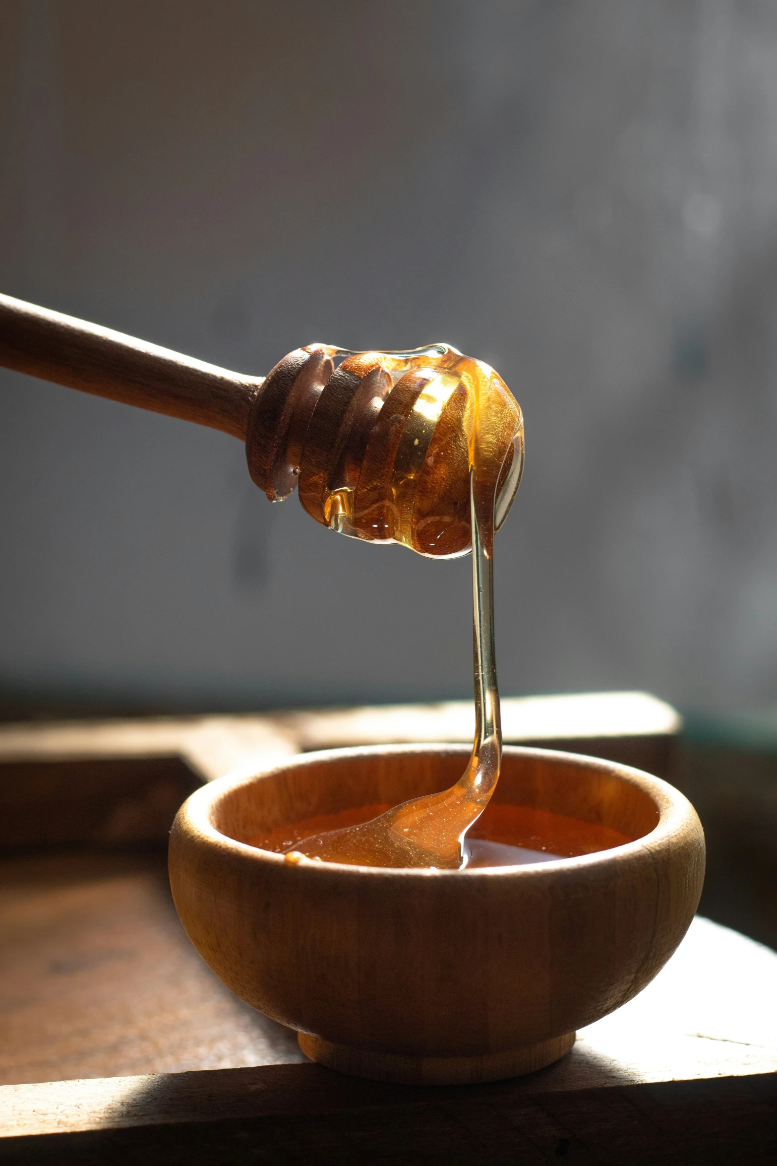 a spoon full of honey sitting in a small bowl