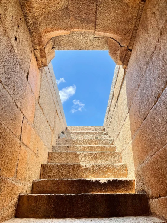 a narrow flight of stone stairs leading up to a bright blue sky