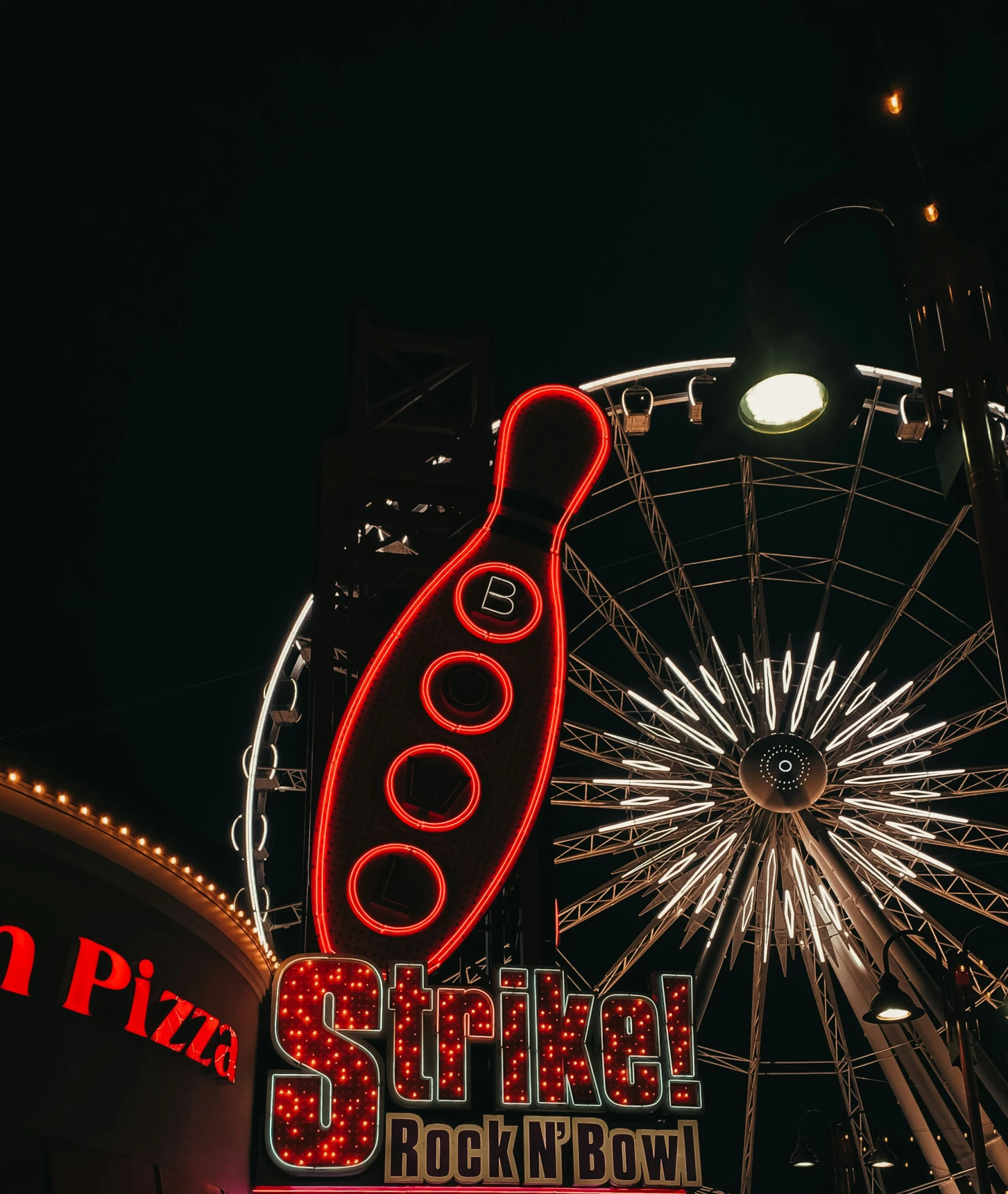 a large neon sign in front of the ferris wheel