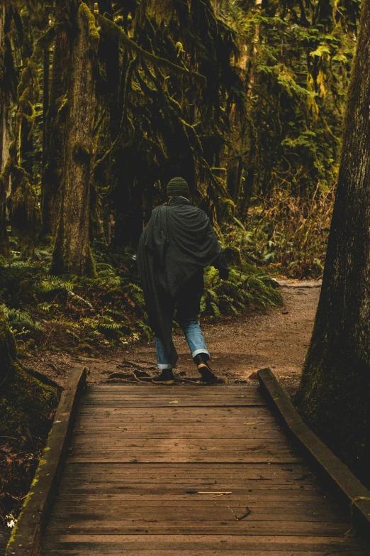 a man with a jacket is walking over a bridge