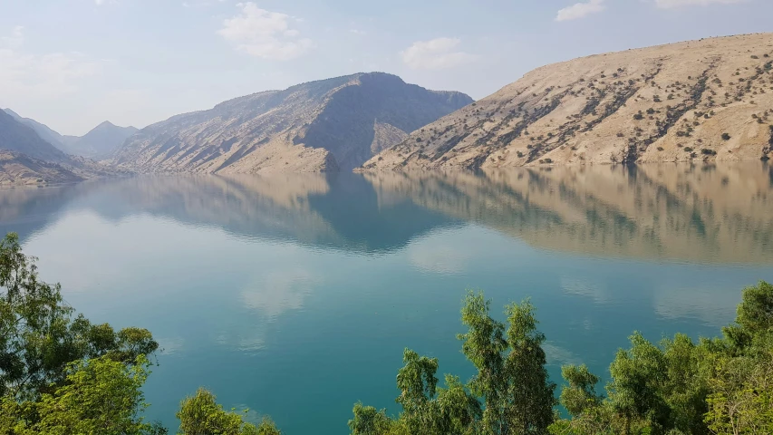 mountains surround a large lake and trees in front