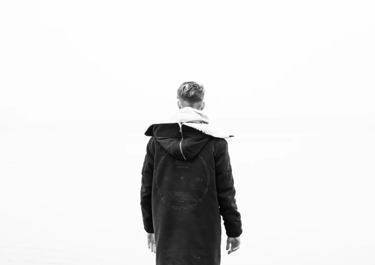 a person standing near the water wearing a coat