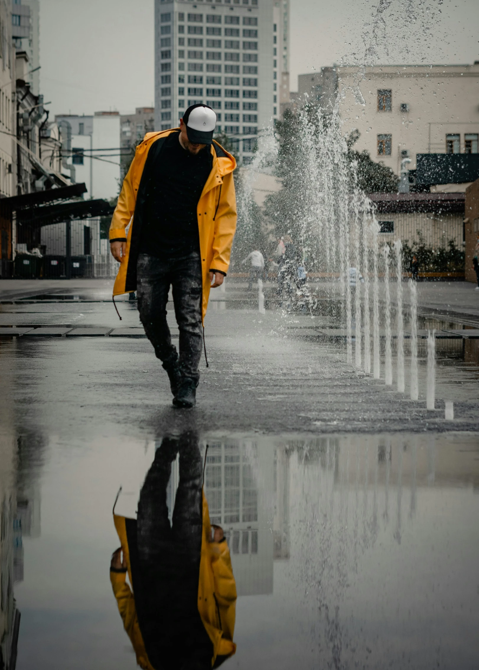 a man is walking on a rainy day near some water fountains