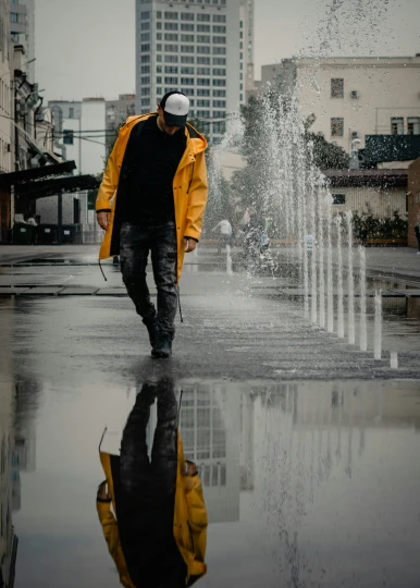 a man is walking on a rainy day near some water fountains