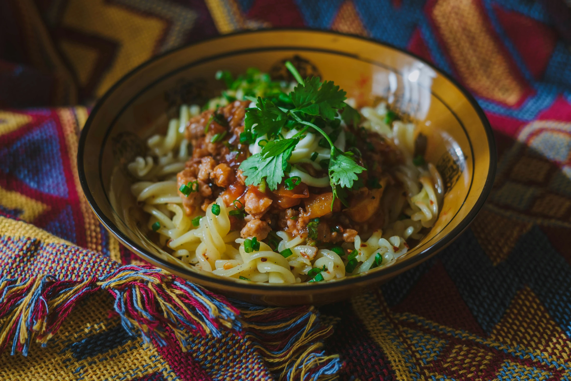 a bowl filled with pasta and meat, next to a cloth