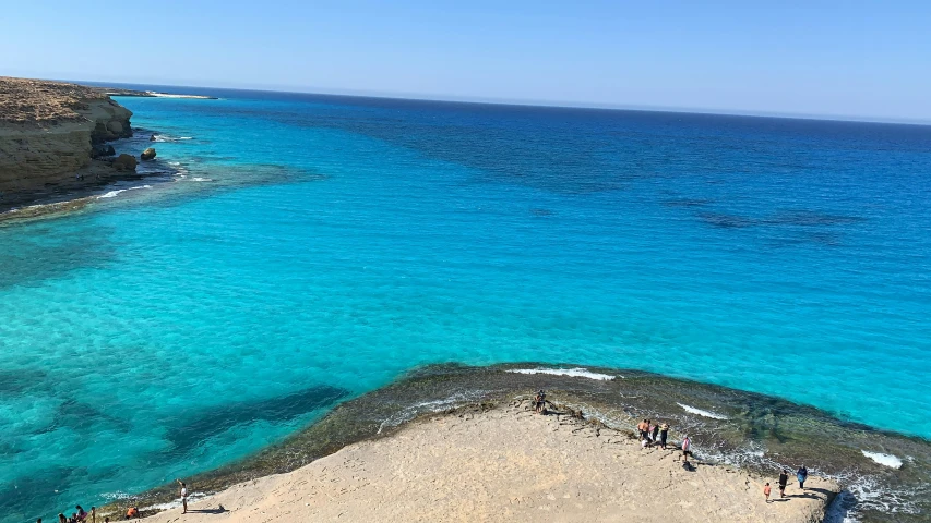 people are standing on a cliff overlooking the water