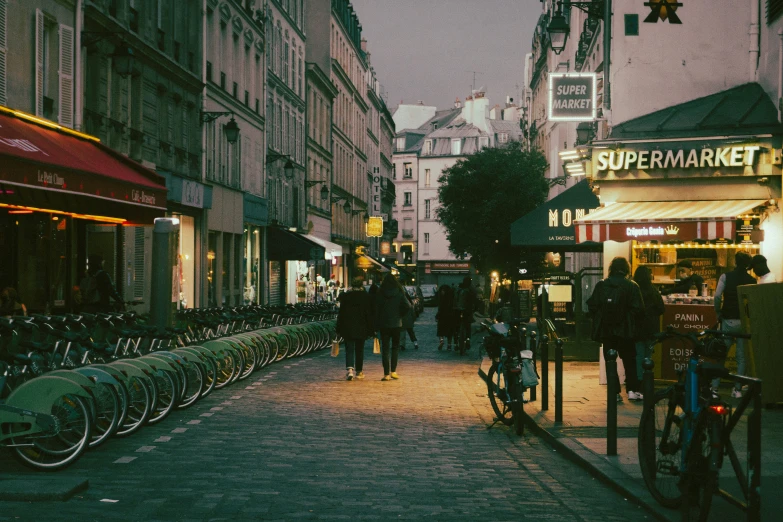 people walk down a city street near parked bikes