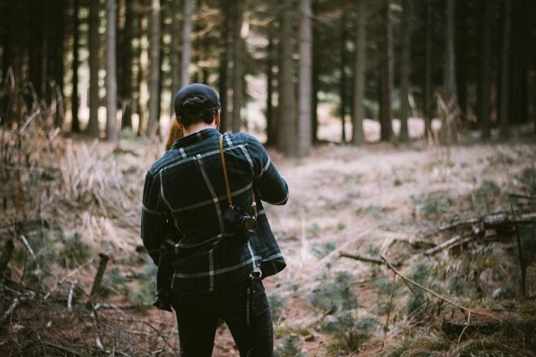 a man wearing a baseball cap is standing in the woods