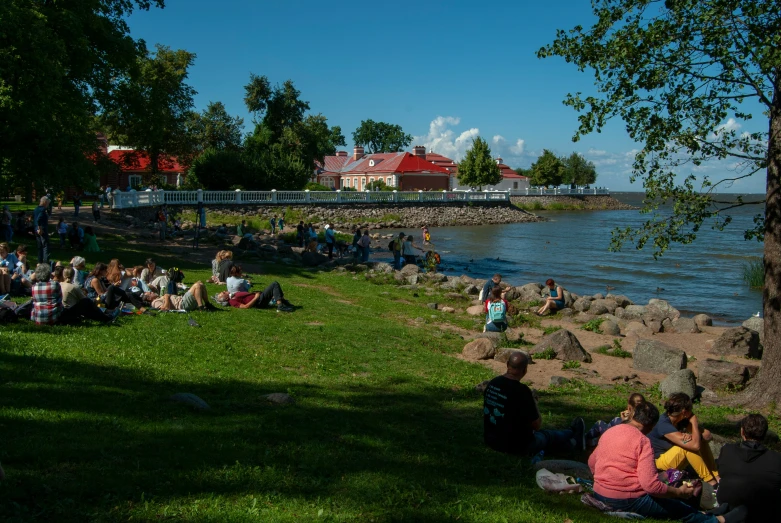 people enjoying the shade near the water at a park