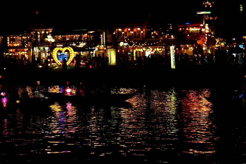 brightly lit boats on a river in front of a city