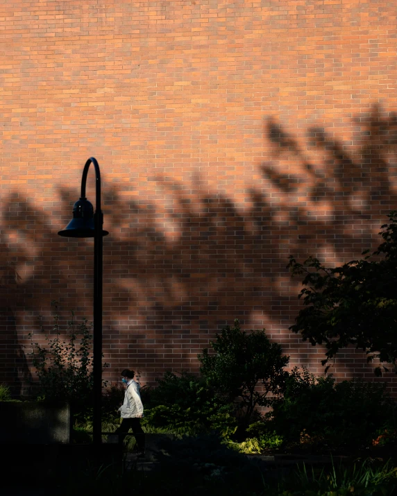 a person standing in the shade under a lamp post