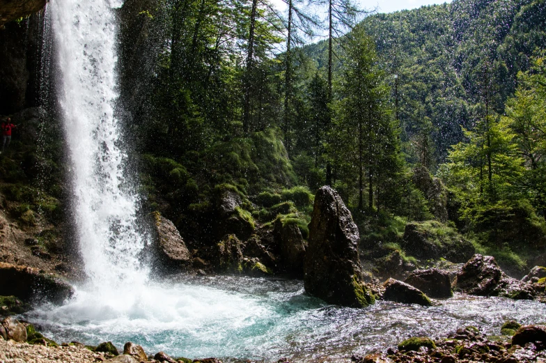 a man standing in the foreground near a waterfall