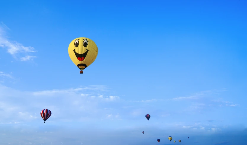 several balloons with faces are flying high in the sky