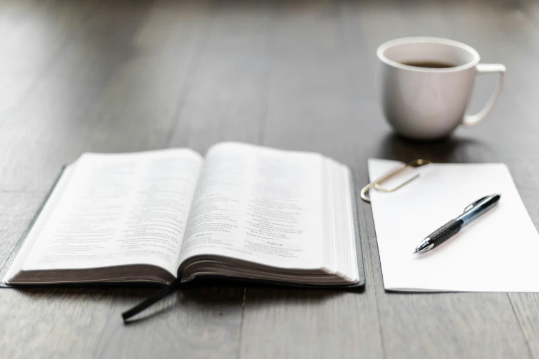 a notebook, pen, and coffee cup sitting on a desk