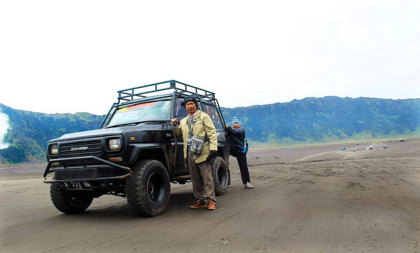 three people posing in front of the top of a vehicle