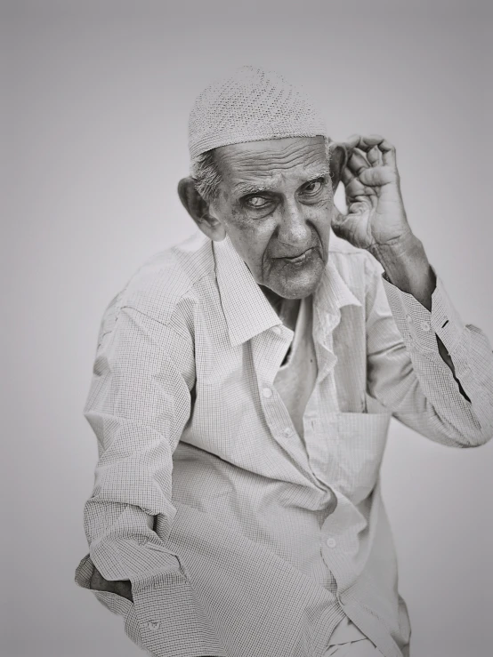 an old man with a white outfit on is holding his head