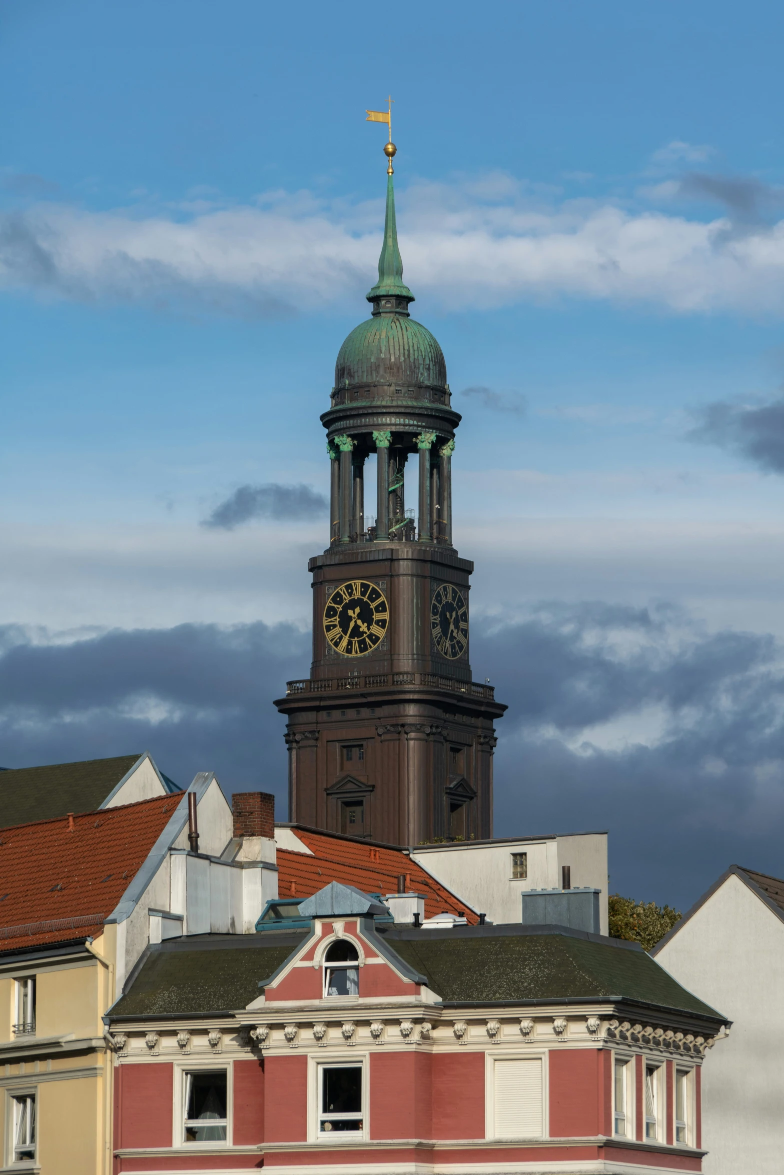 a steeple with a clock on it stands in front of a row of homes