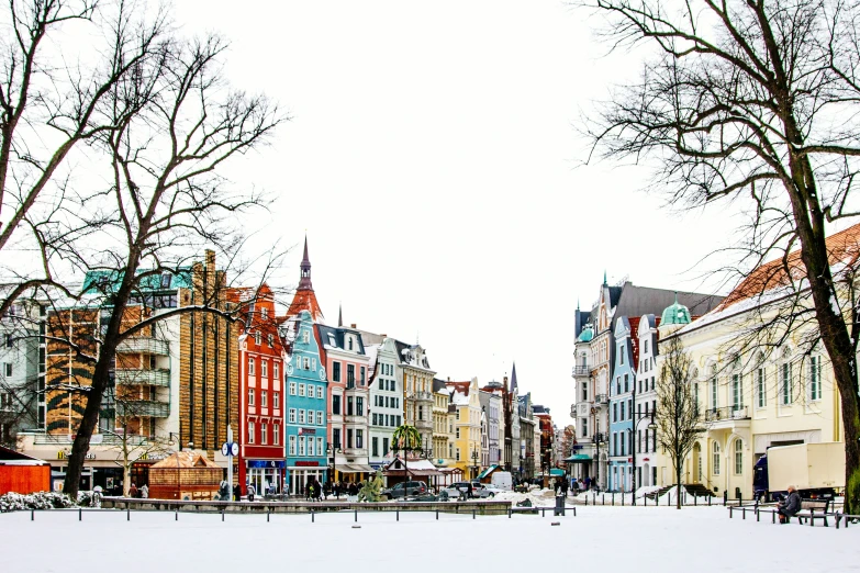 snowy sidewalk and street near trees in front of buildings