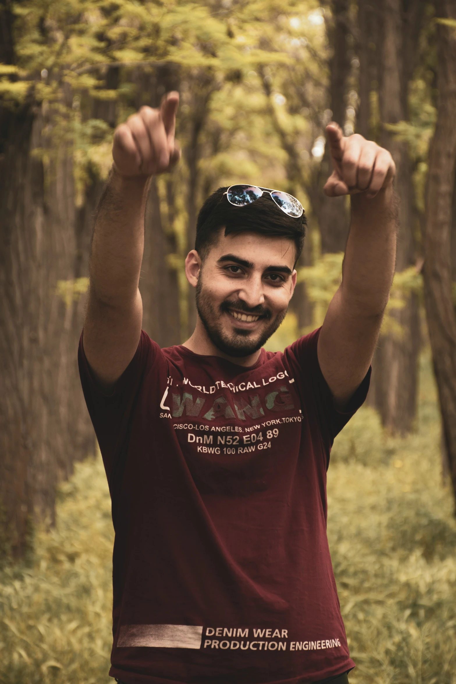 a man is pointing a peace sign in the woods