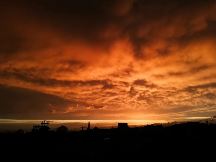 a beautiful red sky and clouds over a village