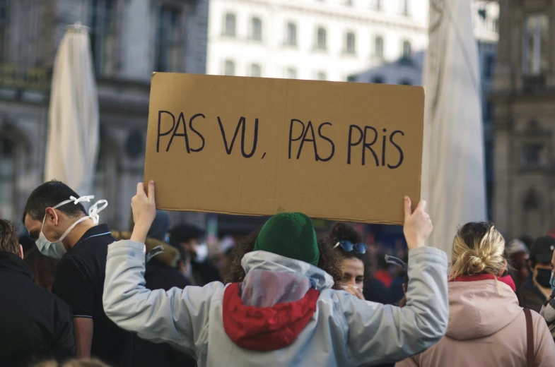 people holding up a cardboard sign in protest