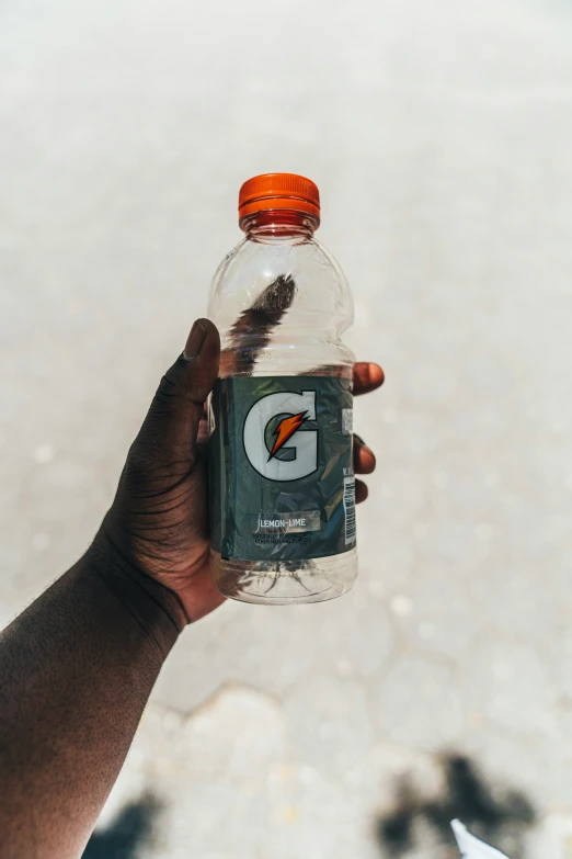 a hand holds a bottle filled with a brown substance