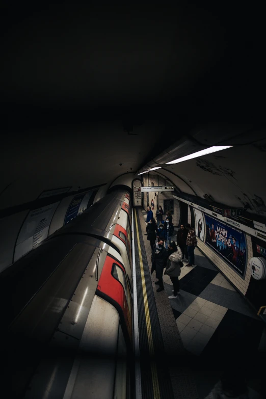 a dark subway with people waiting on the platform for it