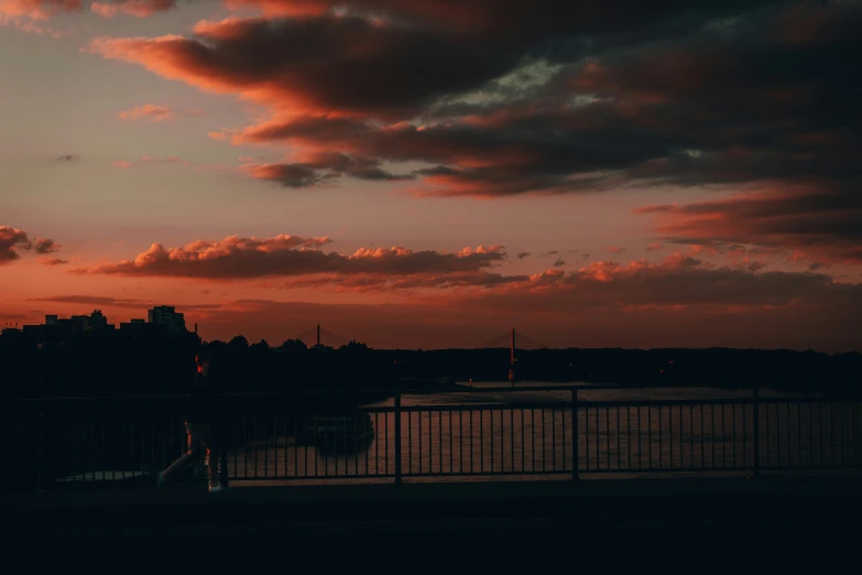 a red sky with clouds and some water