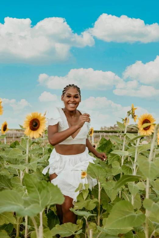 a woman in a sunflower field standing with a dress on