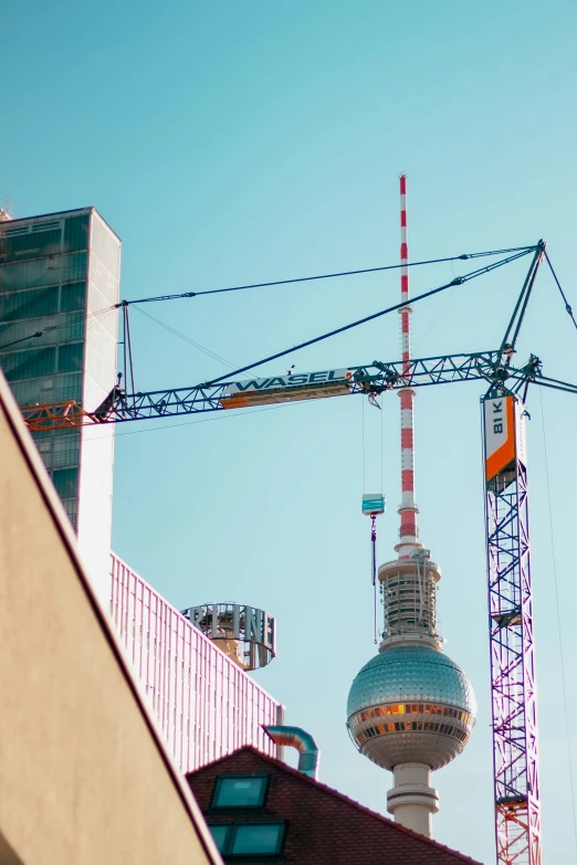 construction cranes sit next to buildings and under a bright blue sky