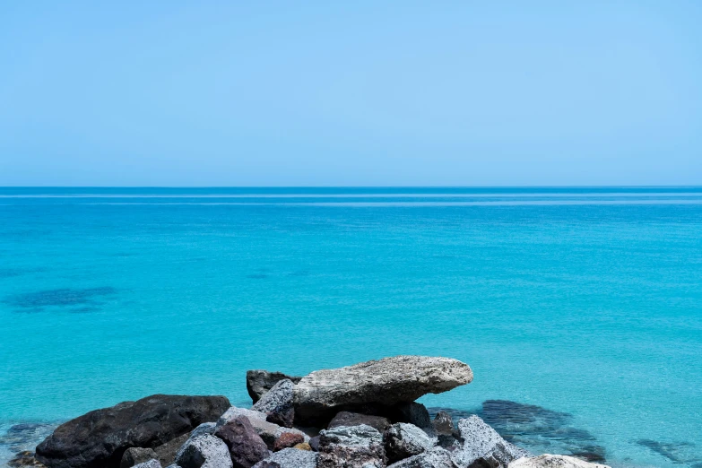 some rocks near some water and blue sky