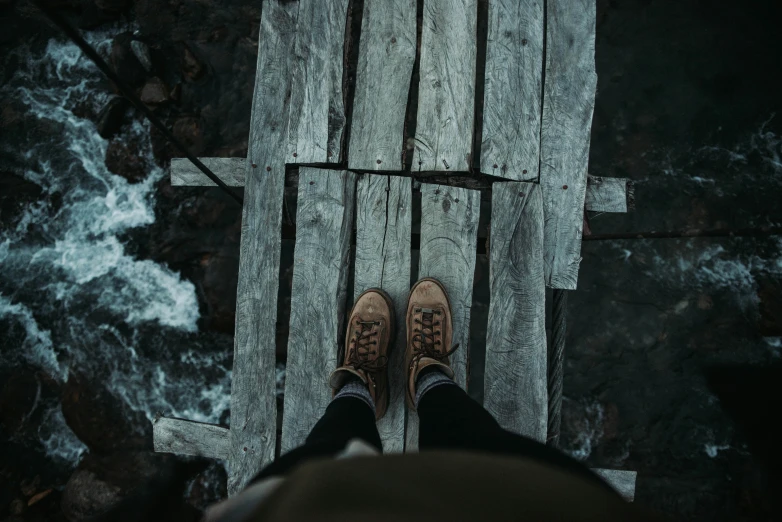 a person stands on a wooden plank, with the top of them