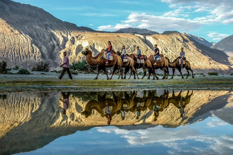 two people on horses are following three men across the water