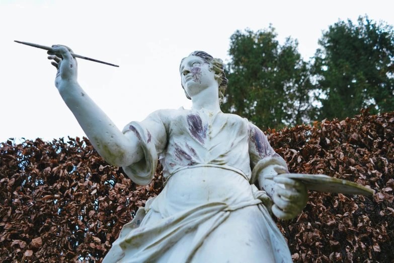 a white statue holding a stick with another stick in his hand