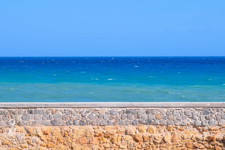 the ocean has a man sitting on a bench