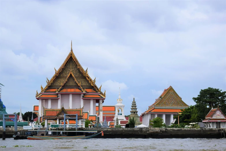 several thai buildings are lined up on the water