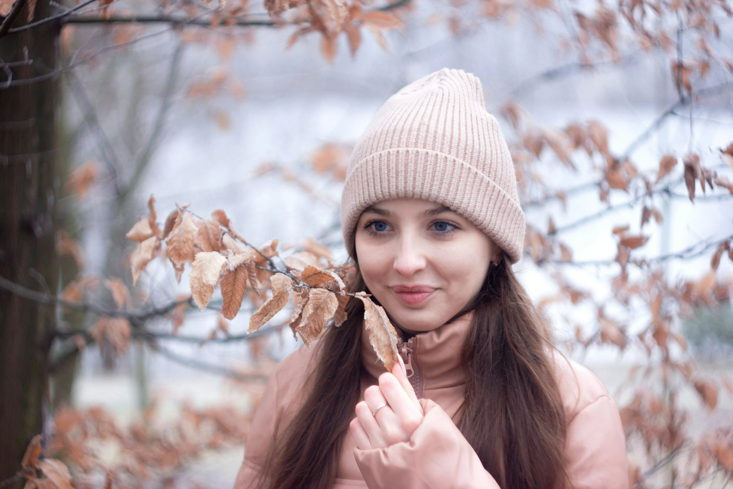 the girl in a beanie holds on to an acorn from a tree