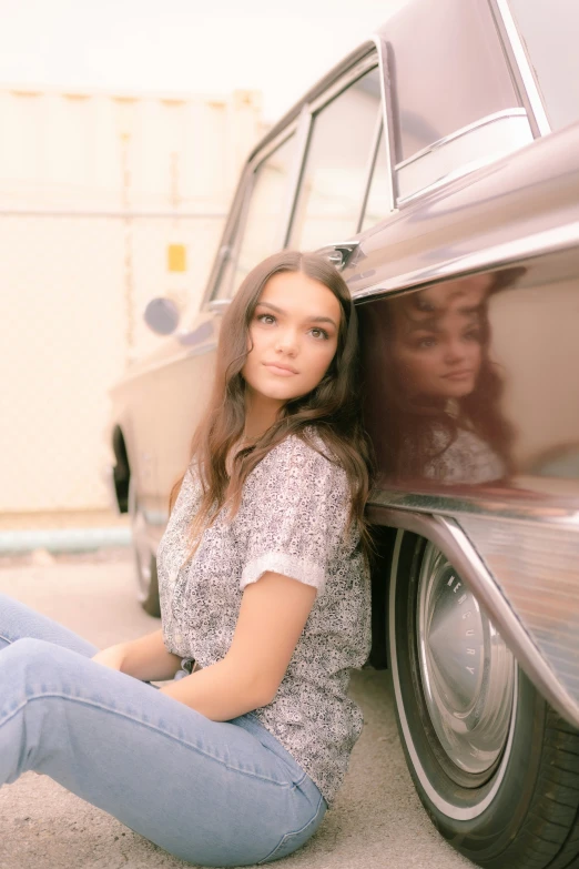 a woman sitting in front of a car near a building