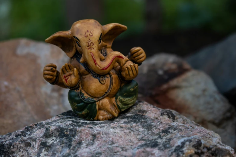 a small ceramic statue sitting on top of a stone