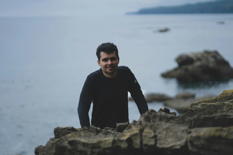 a man standing on top of a rock formation next to the ocean