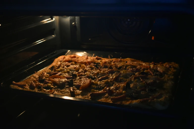 an oven containing a pizza and pan with toppings